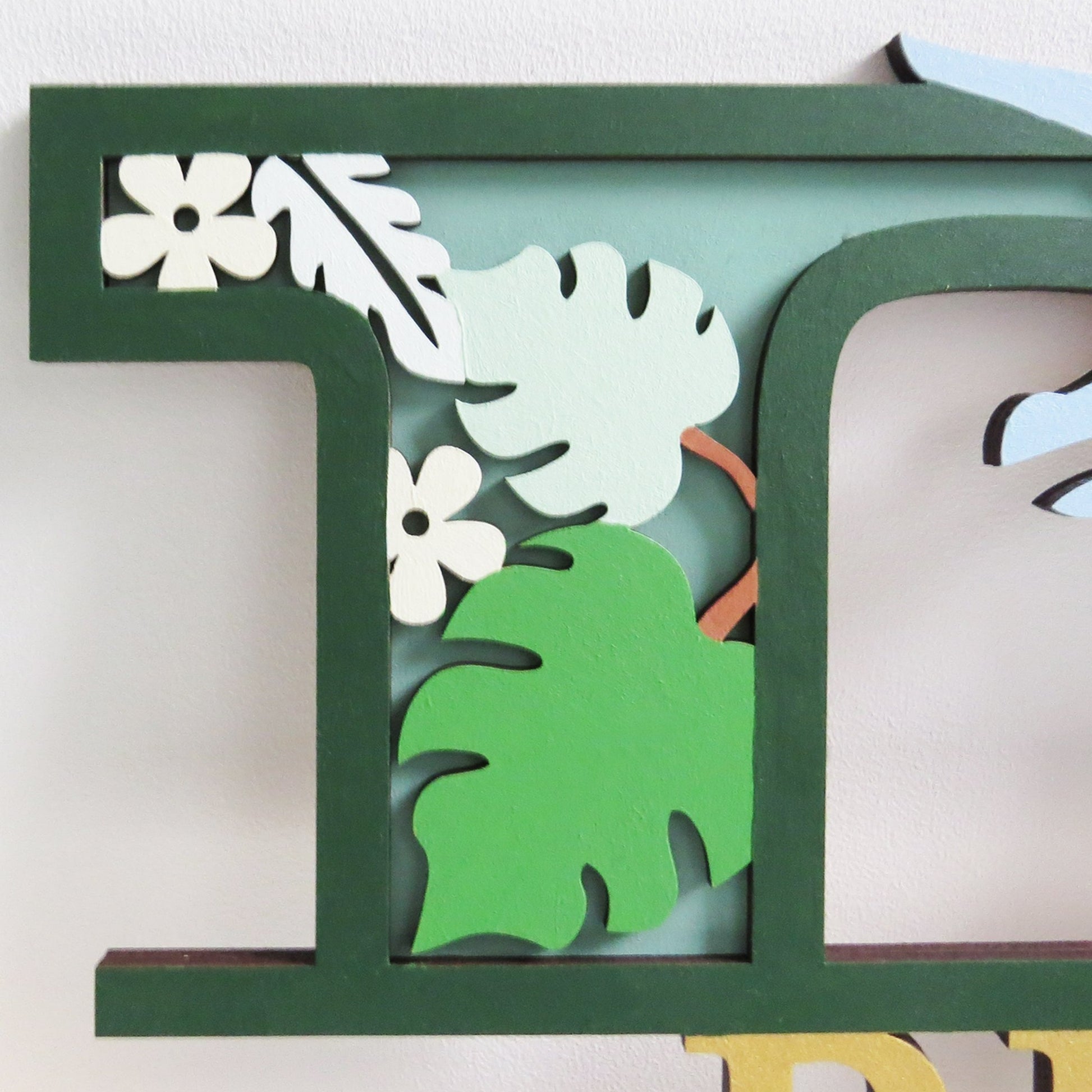 Personalised kids dinosaur themed letter painted in shades of green.