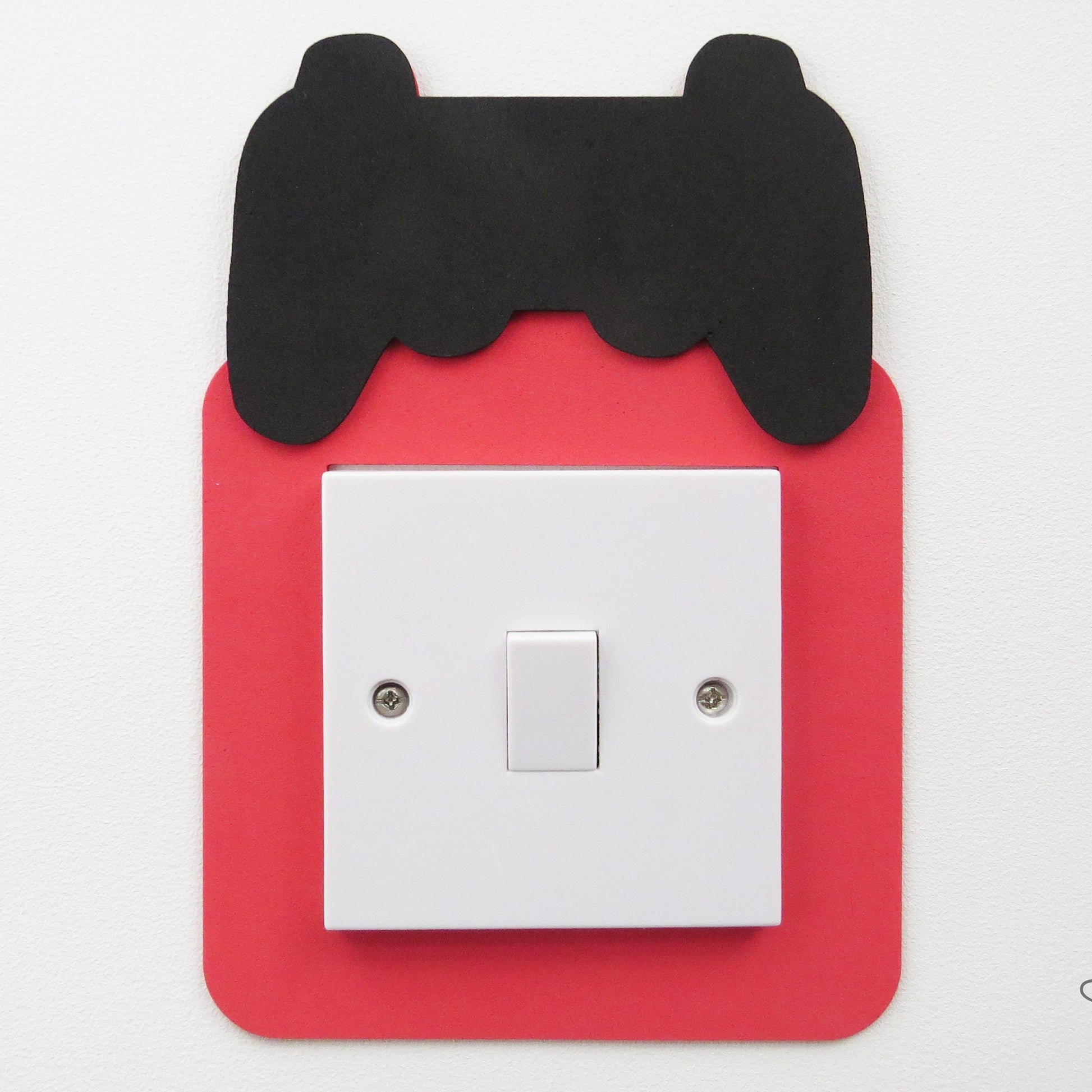 A childrens light switch surround in the shape of a gaming controller.