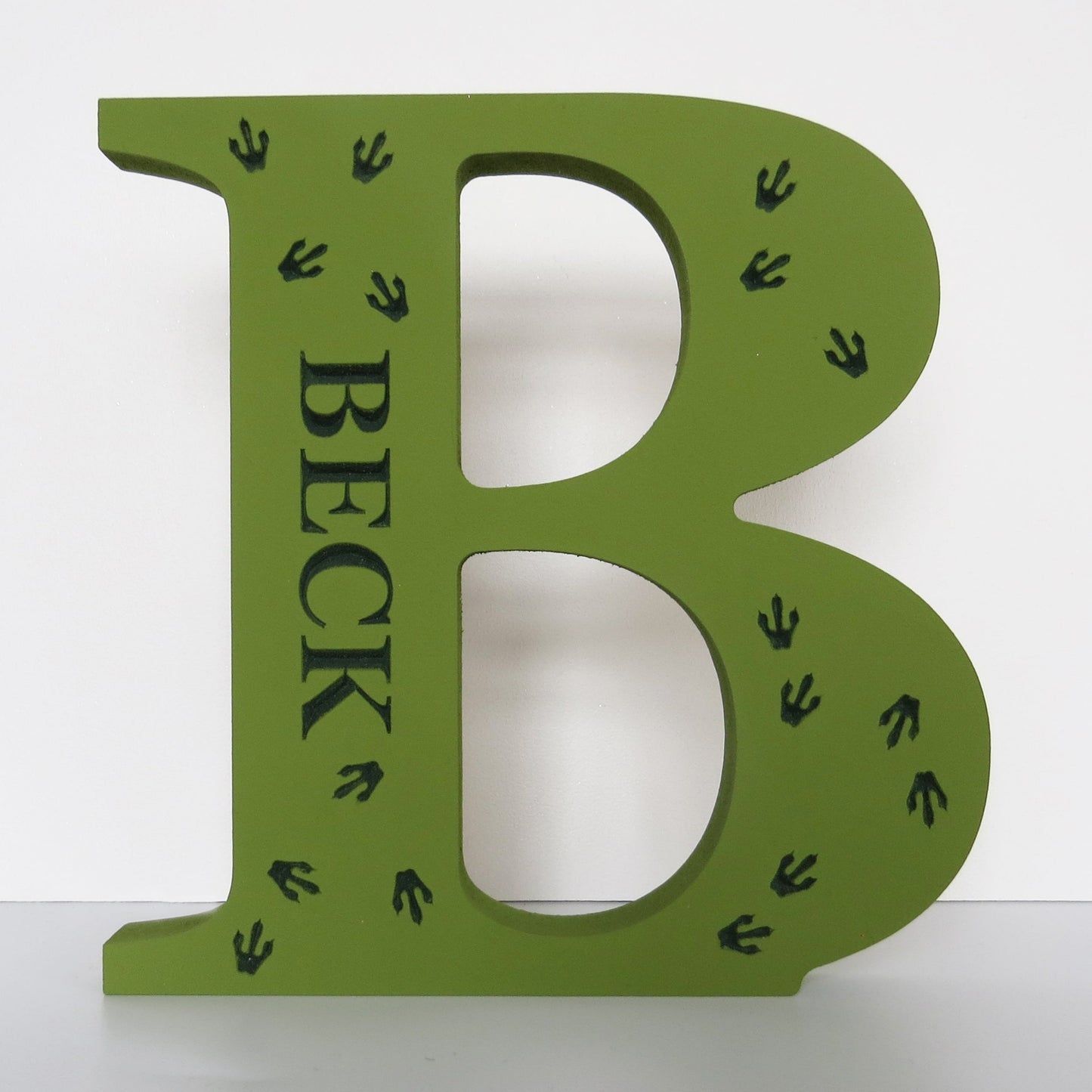 Freestanding letter painted in green with engraved custom name and dinosur foot prints.