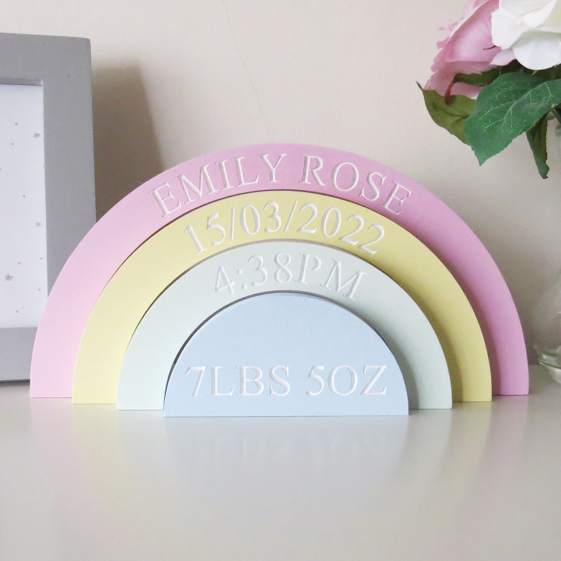 A childrens nurery rainbow shaped shelf stacker painted in pastel colours.