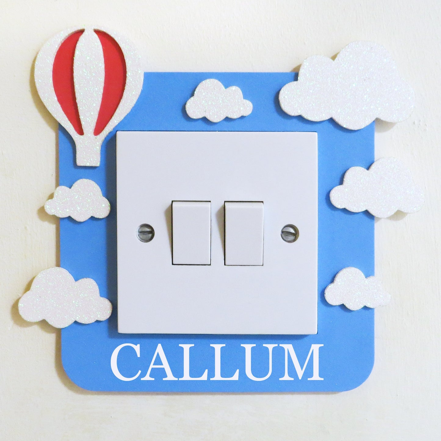 Blue foam light switch surround deigned with a hot air ballon, clouds and a custom name.
