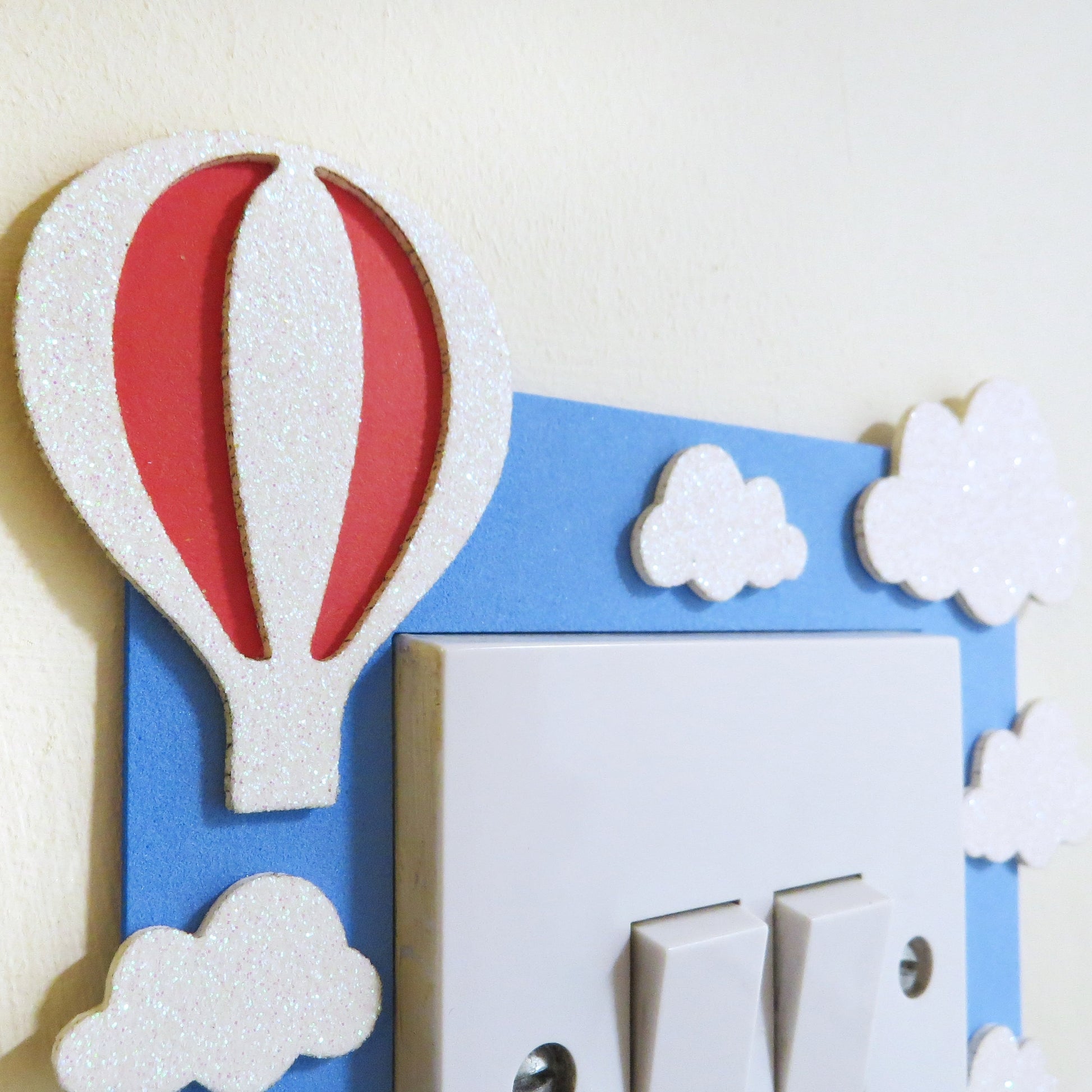Blue foam light switch surround deigned with a hot air ballon, clouds and a custom name.